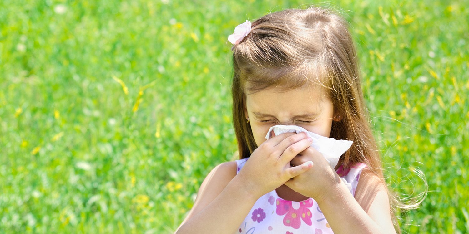 a girl sneezing in a summery field